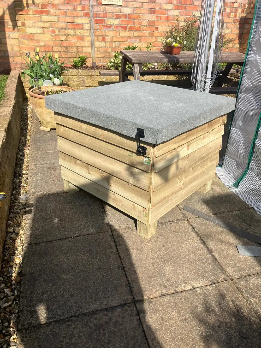 Bespoke timber garden storage box with a stone slab lid on a patio