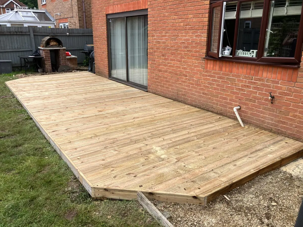 Timber decking boards laid across a level sub frame beside a house