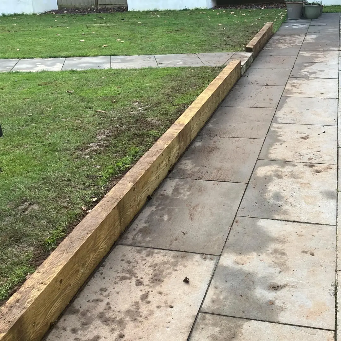 Railway sleeper edging laid between a lawn and a paved path
