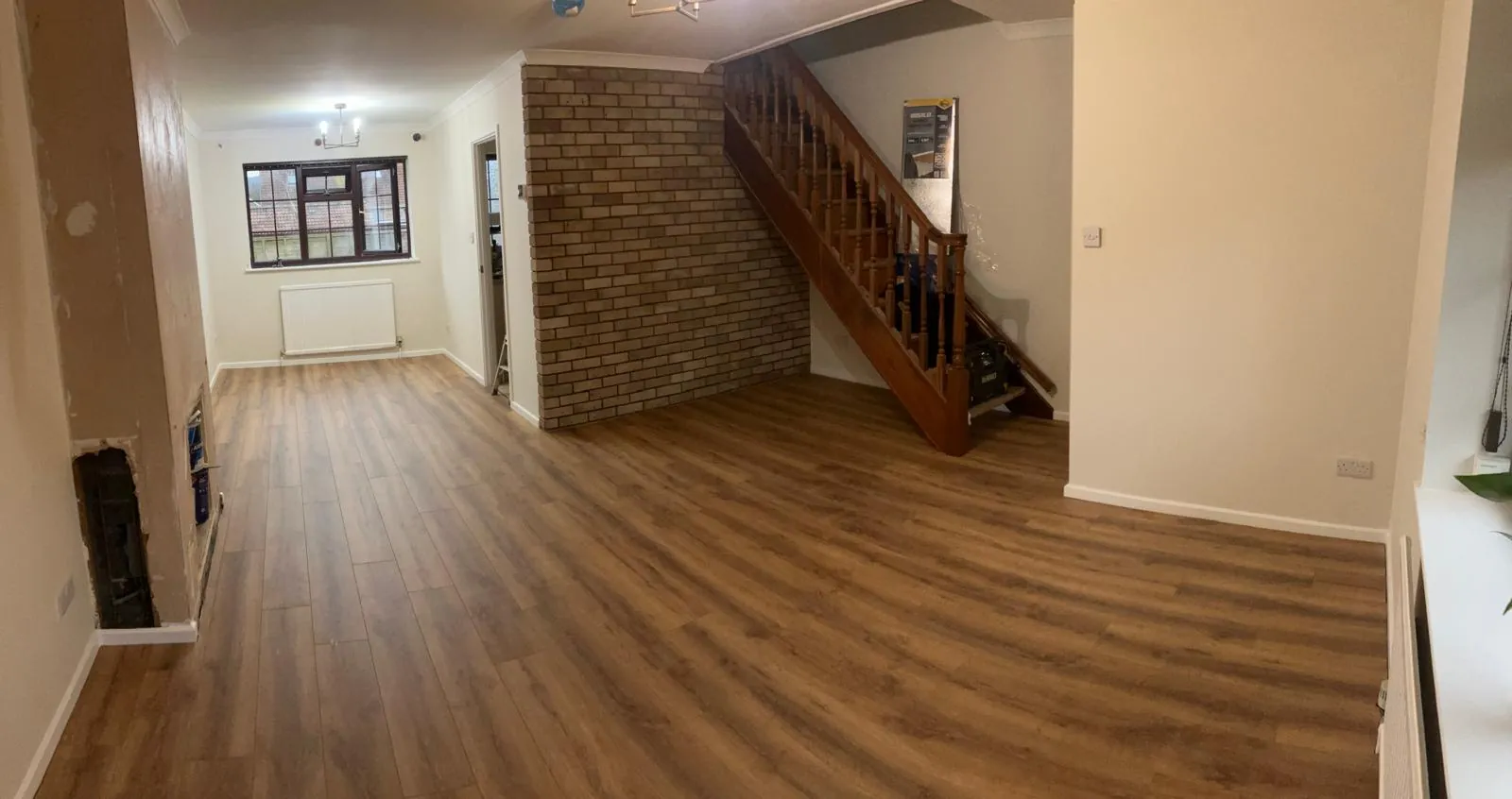 Laminate flooring fitted through an open plan living room and hallway with a staircase