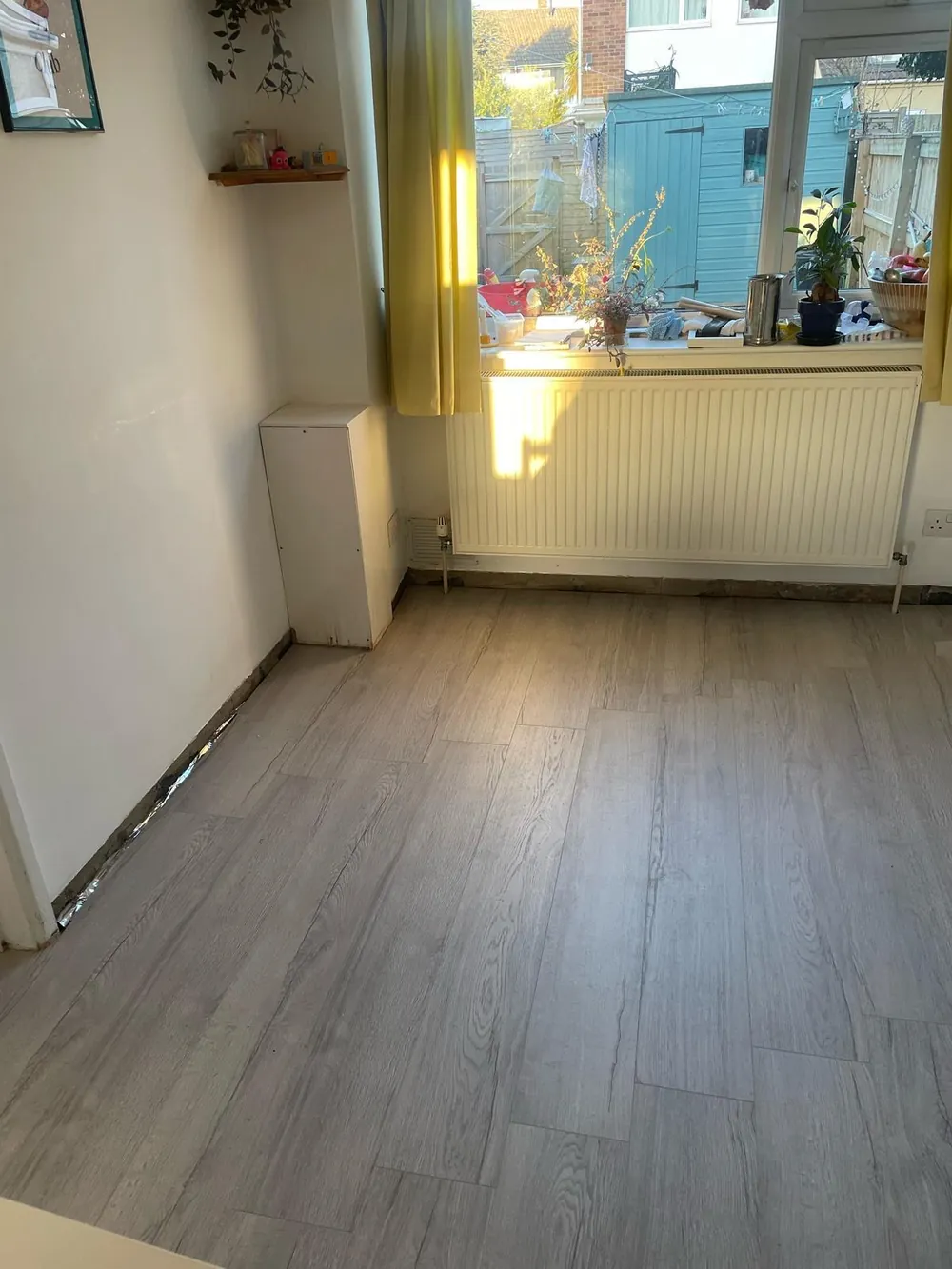 Grey vinyl plank flooring fitted in a room with a radiator and window